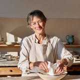 Potter wrapping a finished bowl in tissue paper