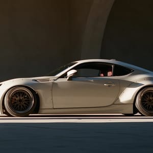A sleek Japanese sports coupe featuring a wide body kit with flared fenders, a deep front splitter, and a large rear wing, photographed dramatically from a low angle in sharp side light.