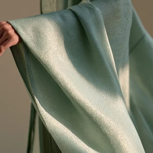 An ancient Chinese noblewoman wears a flowing silk robe with the translucent, jade-green sheen of a celadon glaze.