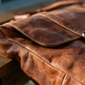 A rugged vintage camera bag made of rich cognac-colored distressed leather with natural creases and soft scuffs.