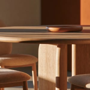 A huddle room with a round wooden table and upholstered chairs, soft window light, warm earthy colors, and a calm, focused atmosphere.