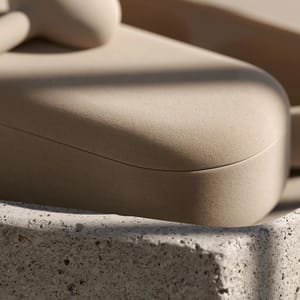 A minimalist product macro highlighting the velvety matte texture of a wireless earbud case resting on a piece of smooth raw concrete.