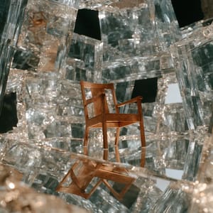 A solitary wooden armchair fractures into an infinite, folding kaleidoscope of glass planes within a surreal mirror dimension.