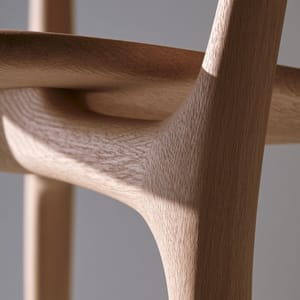 A close-up of a minimalist wooden chair showcasing its seamless wooden joinery under soft, diffused studio lighting.