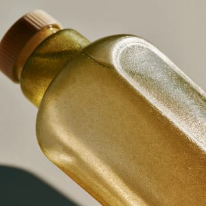 A minimalist water bottle made of seaweed bioplastic glows with soft sunlight, showing its organic, semi-translucent texture.