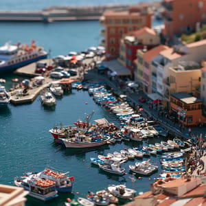 Midjourney Demo Prompt: a busy harbor town from a high clifftop, tilt-shift miniature, one razor-thin band of focus across the tiny boats and quay, everything above and below melting to blur, toy-like clarity, bright noon color --ar 3:2 --style raw --s 100 --preview