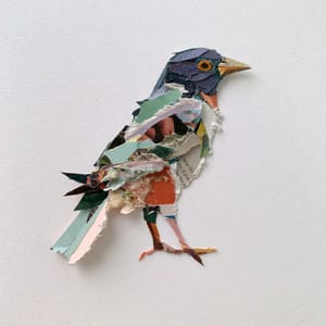 A bird made from torn paper collage, with jagged edges of magazine and newsprint layers visible on a white background.