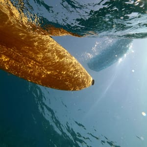 Underwater top-view, looking up from beneath the surface at a pear yellow kayak floating above, water surface distorted with ripples, sunlight streaming down creating caustic patterns on the hull, clear blue water --ar 4:5 --style raw --s 50 --preview