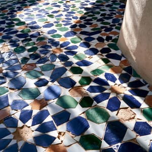 A serene boutique hotel courtyard featuring a beautiful central fountain decorated in intricate zellige tilework.