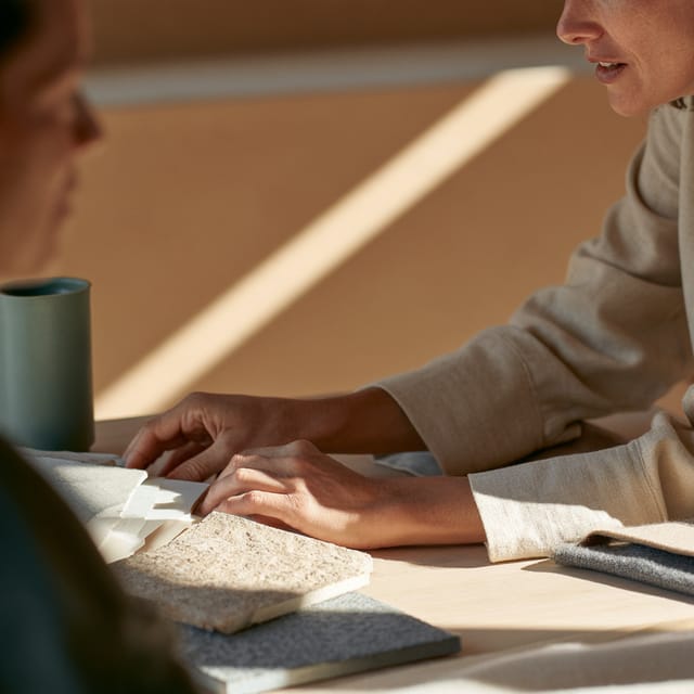 Design consultation presenting material swatches across an oak table