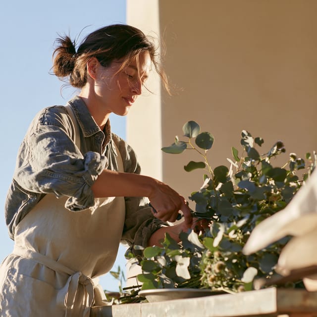 Florist trimming eucalyptus stems at a zinc worktable