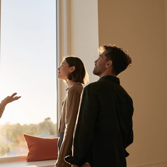 Realtor showing a couple through an empty living room