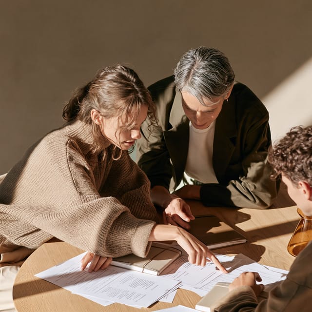 Three partners reviewing an agenda around a round oak table