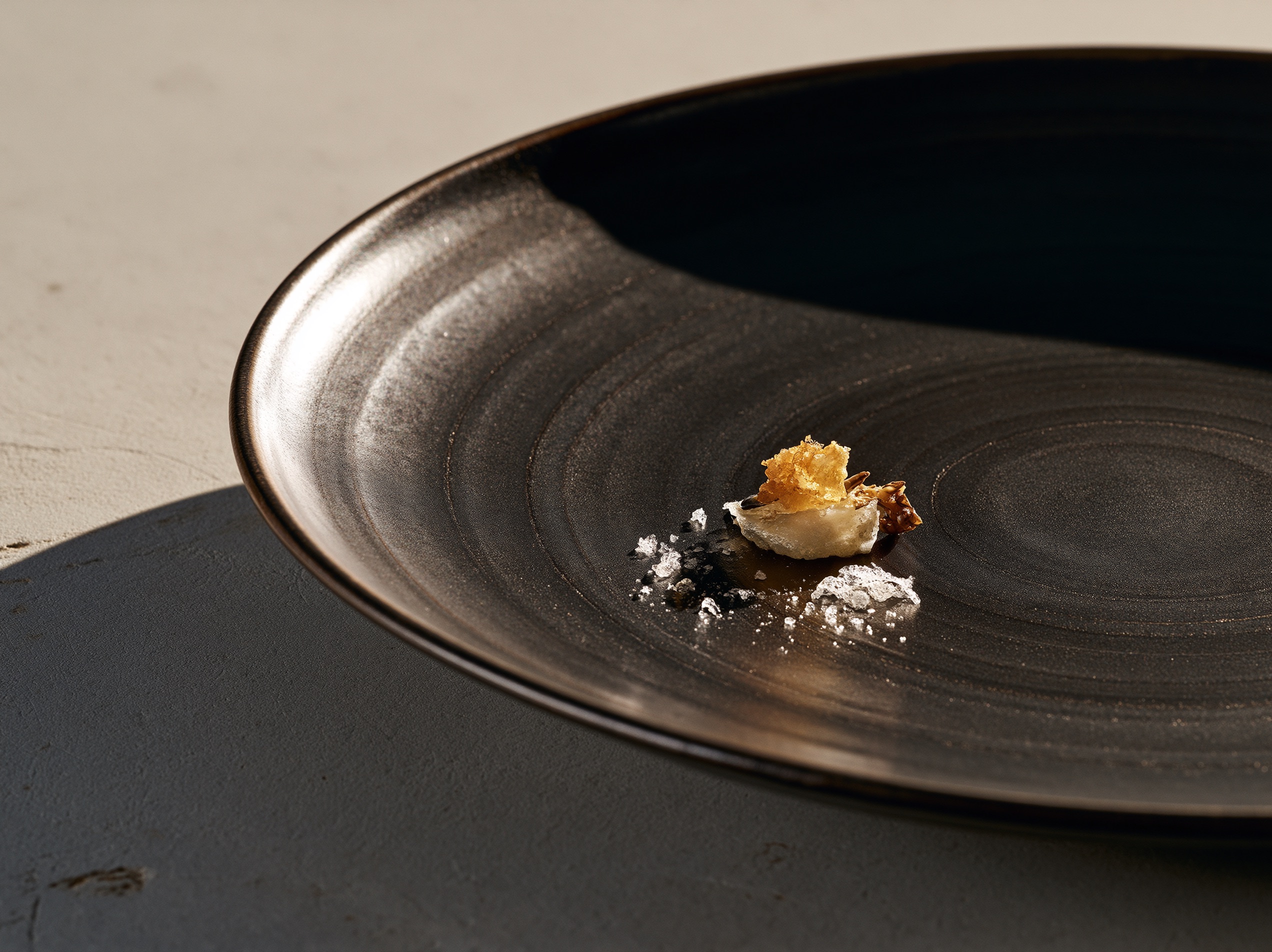 Close-up food photography showcasing asymmetrical plating on a matte ceramic dish with soft window lighting.