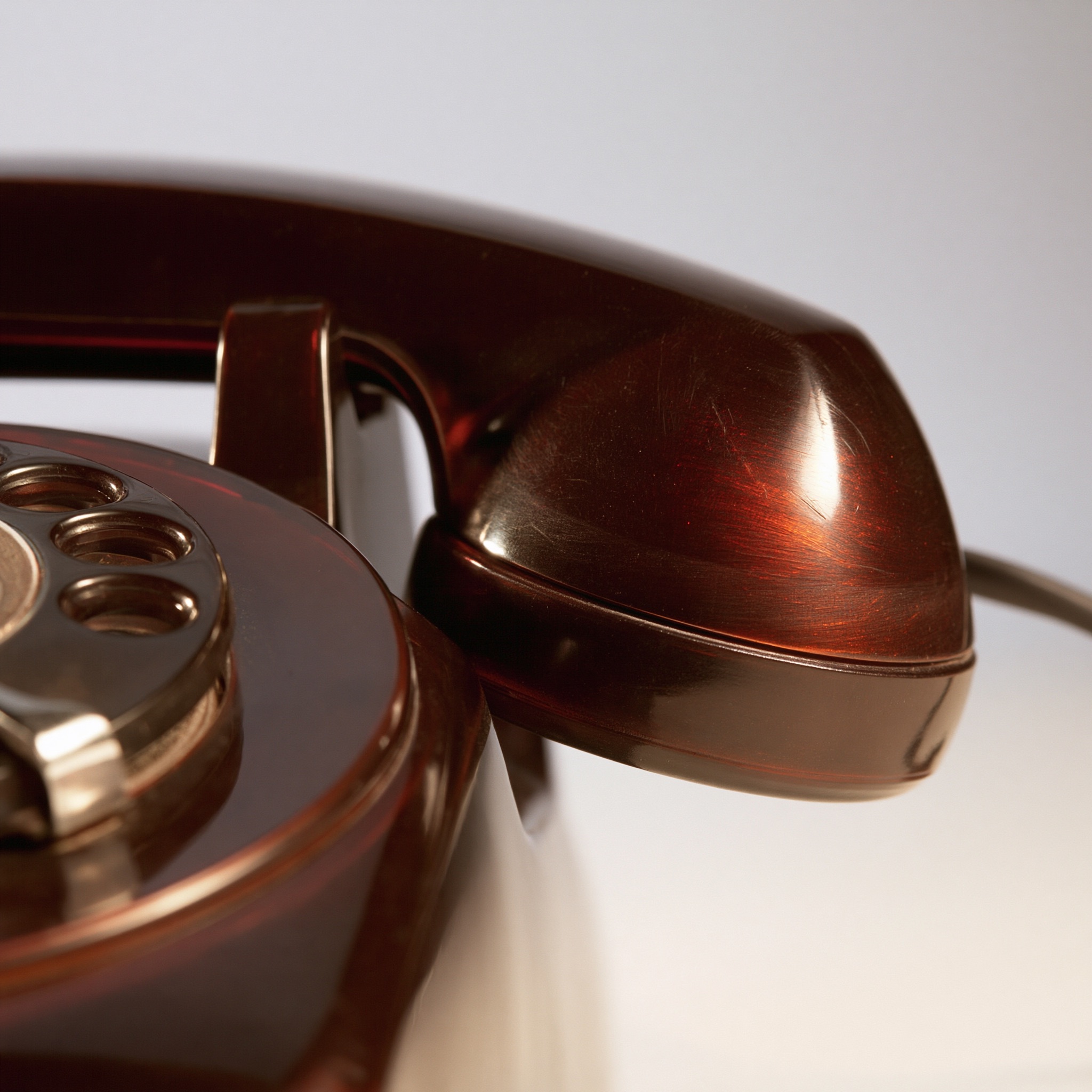 A retro rotary telephone made of Bakelite with a polished amber-brown surface resting against a plain background.