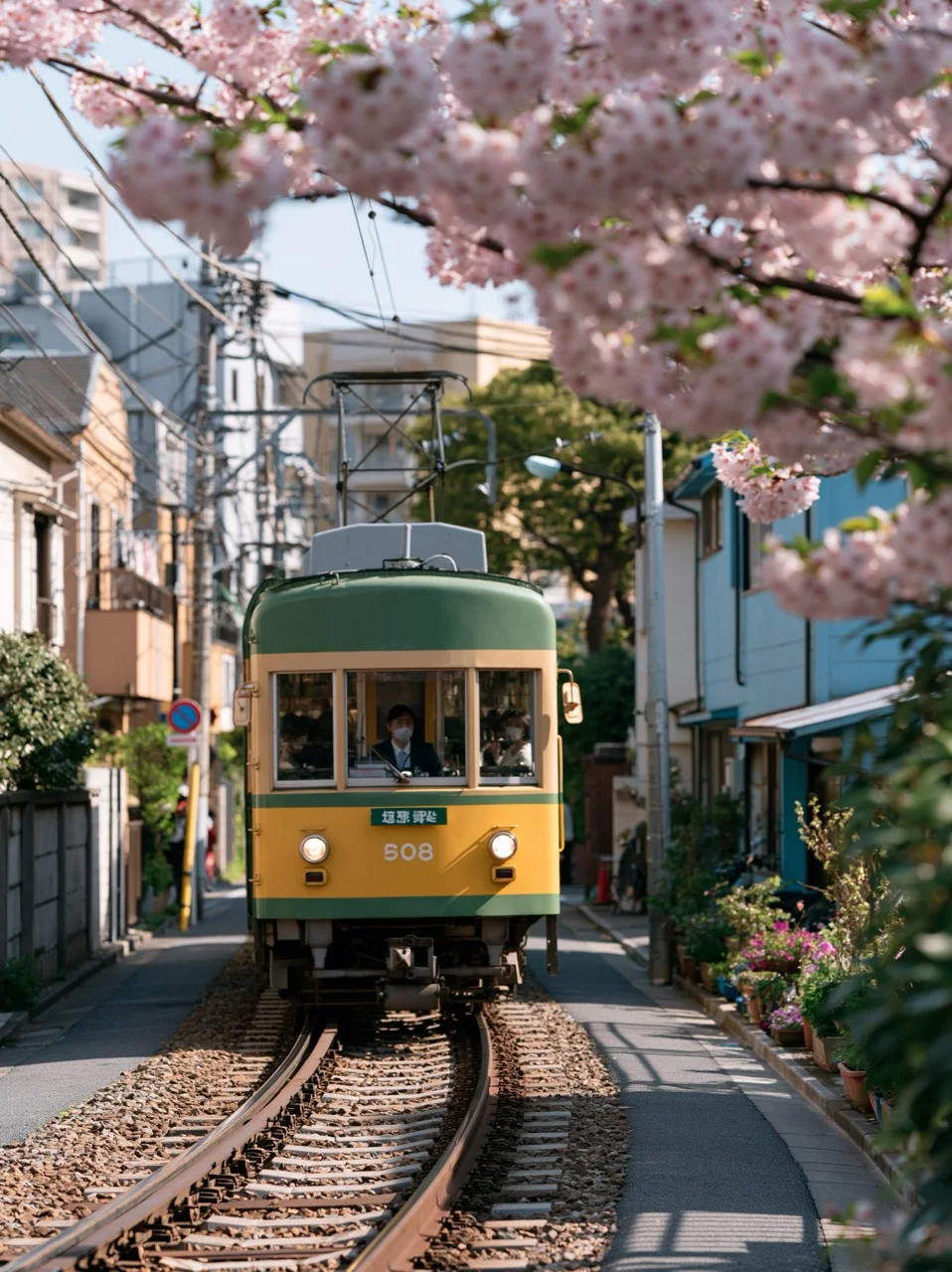A retro yellow and green tram travels down a narrow cherry blossom tram street in Tokyo, framed by blooming sakura trees and soft morning sunlight.