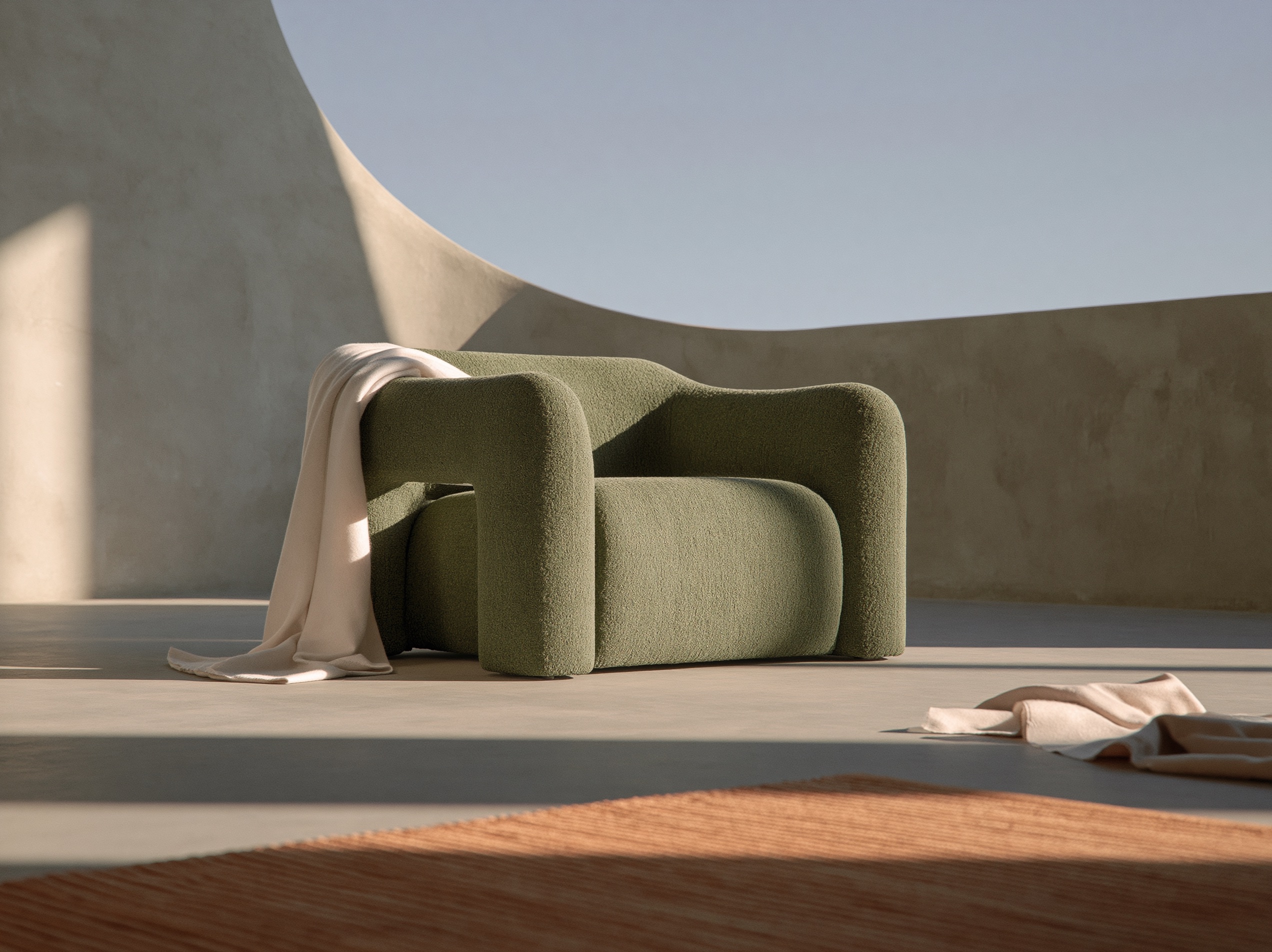 A minimalist armchair upholstered in desaturated spruce green fabric sits in a softly lit, modern concrete room.