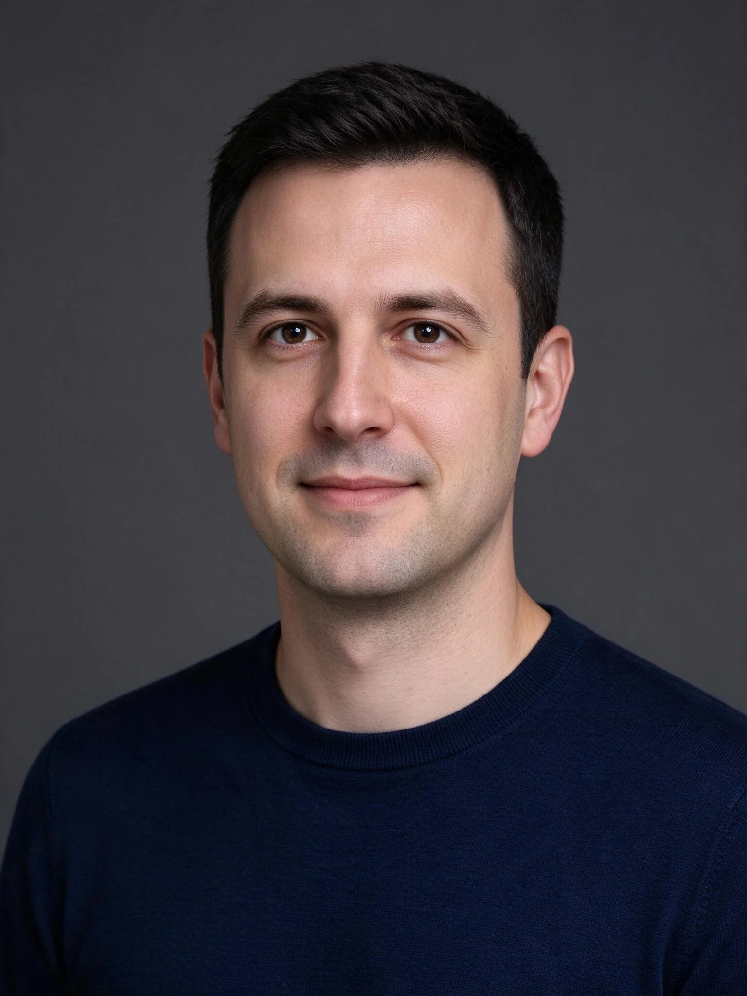 A head and shoulders shot of a man looking toward the camera, framed from the top of his head to just below his shoulders.