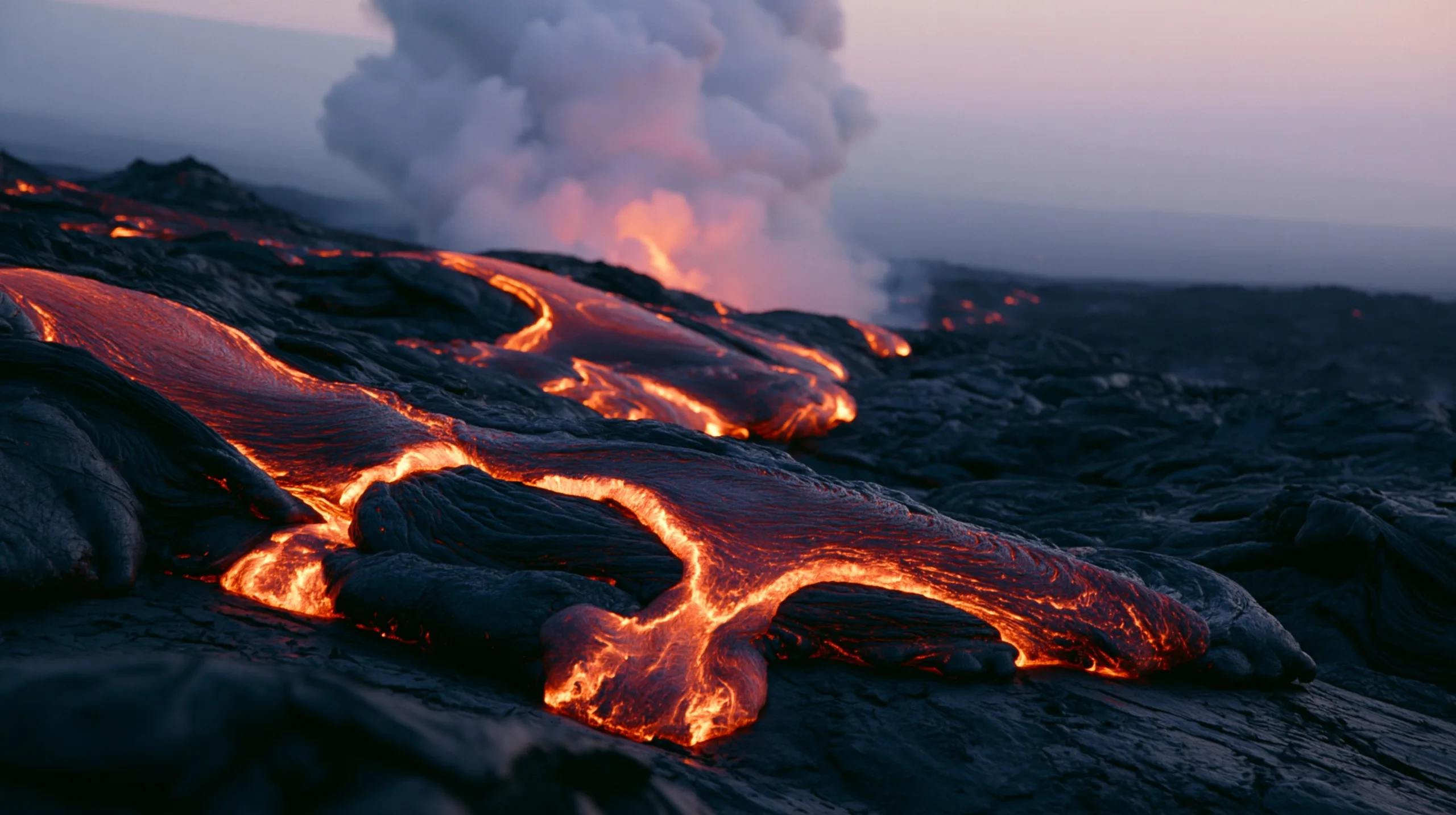 A close-up shot of thick molten lava creeping across a dark volcanic field, its glowing orange cracks breaking through the cooling black crust.