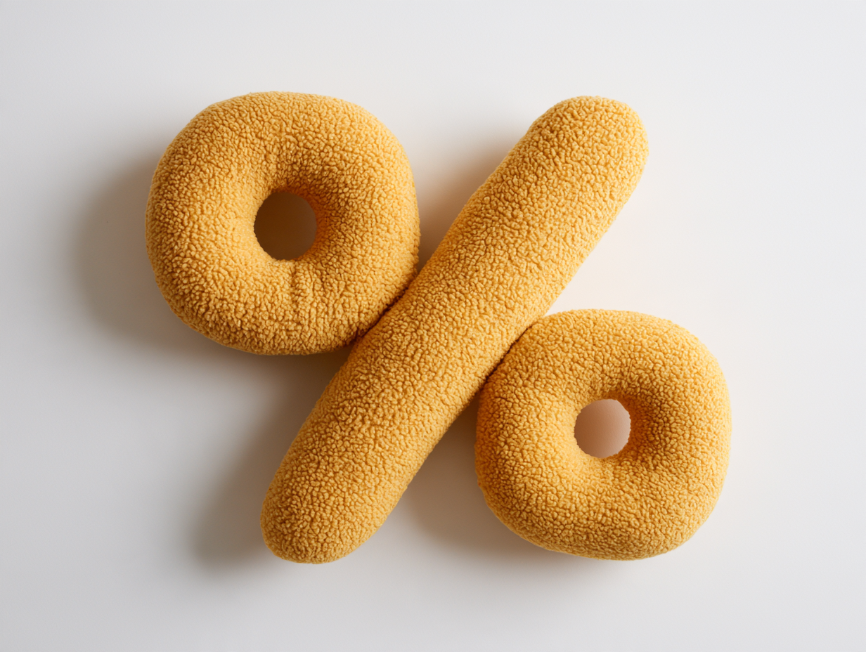 A chunky, cushion-like percent sign in mustard yellow teddy fleece lies flat on a pure white surface, seen from directly above.