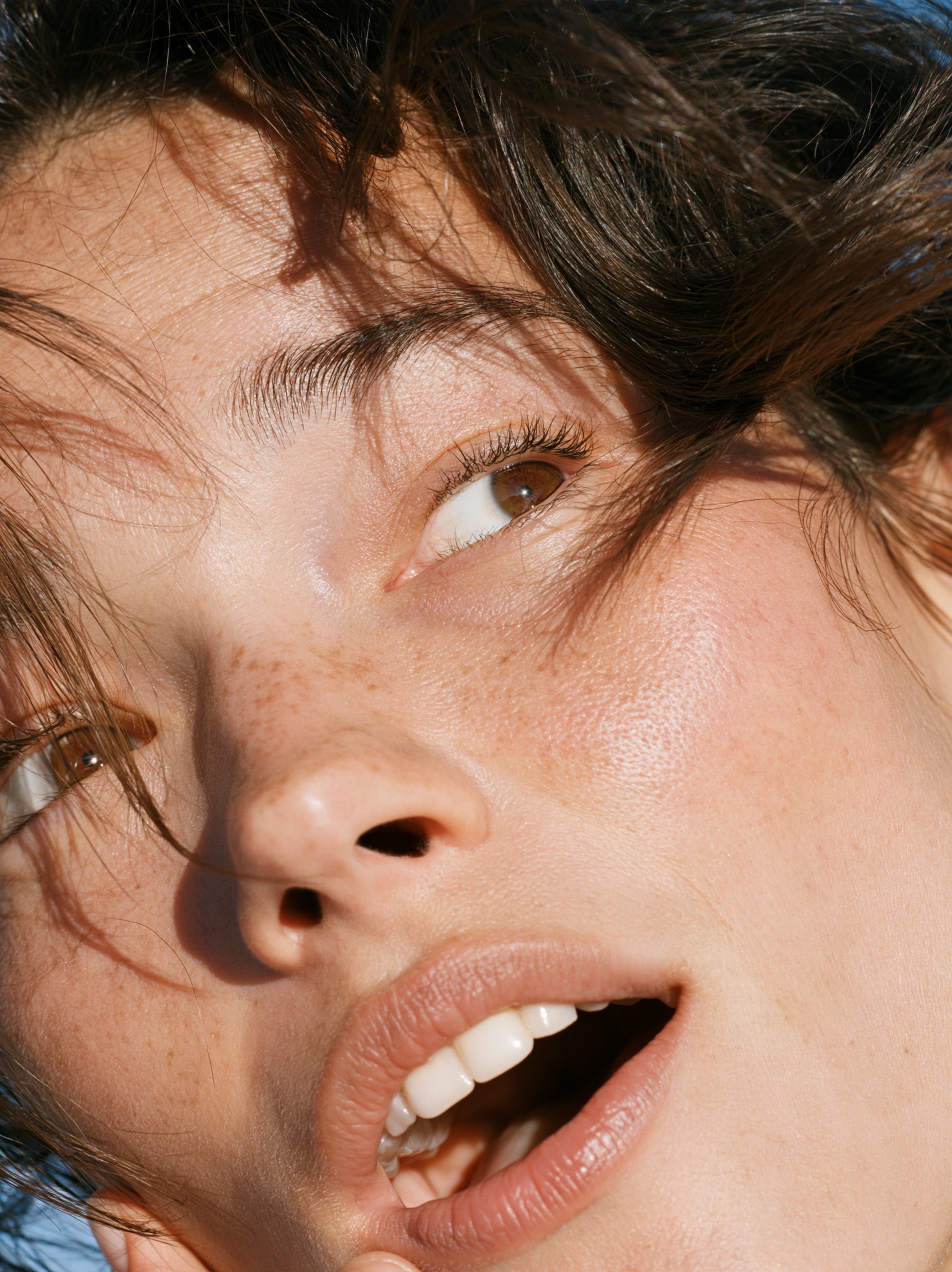 A woman's face with a surprised expression, eyebrows raised and mouth open.