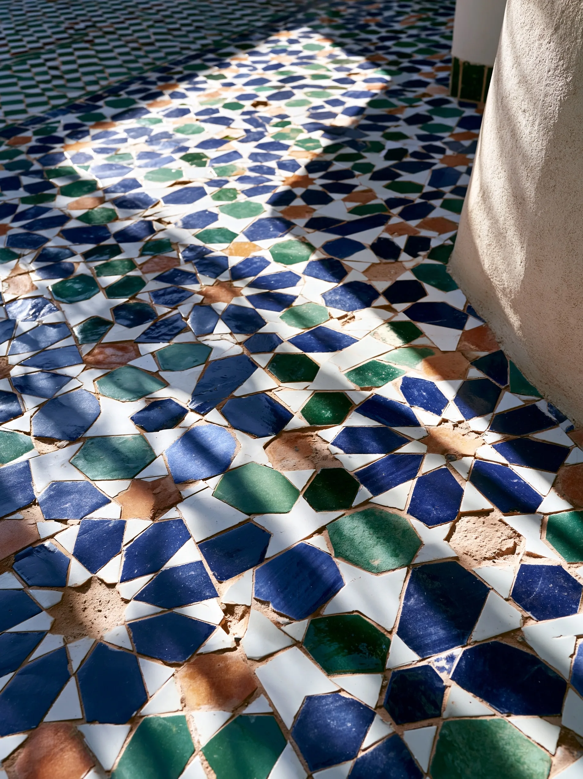 A serene boutique hotel courtyard featuring a beautiful central fountain decorated in intricate zellige tilework.